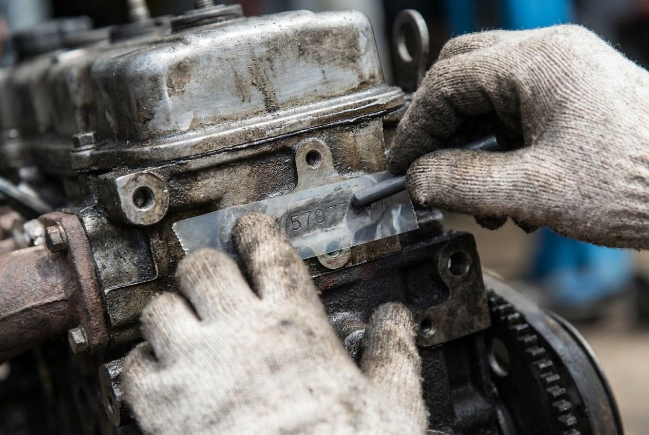 Unas manos con guantes toman la impronta del número del motor con cinta y lápiz